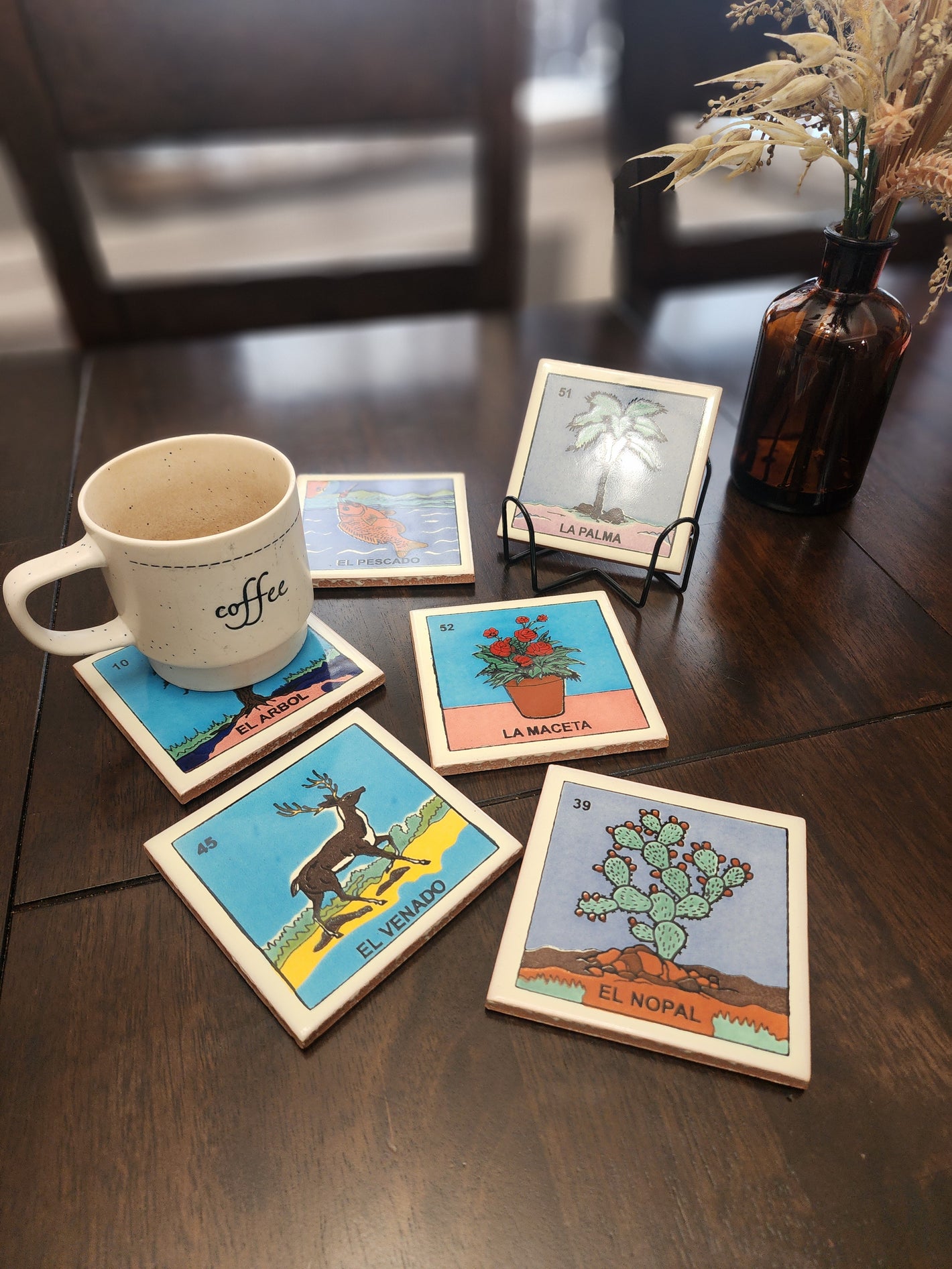 Set of colorful coasters with various designs on a wooden surface, accompanied by a mug.