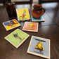 Set of colorful playing loteria inspired ceramic coasters on a wooden surface