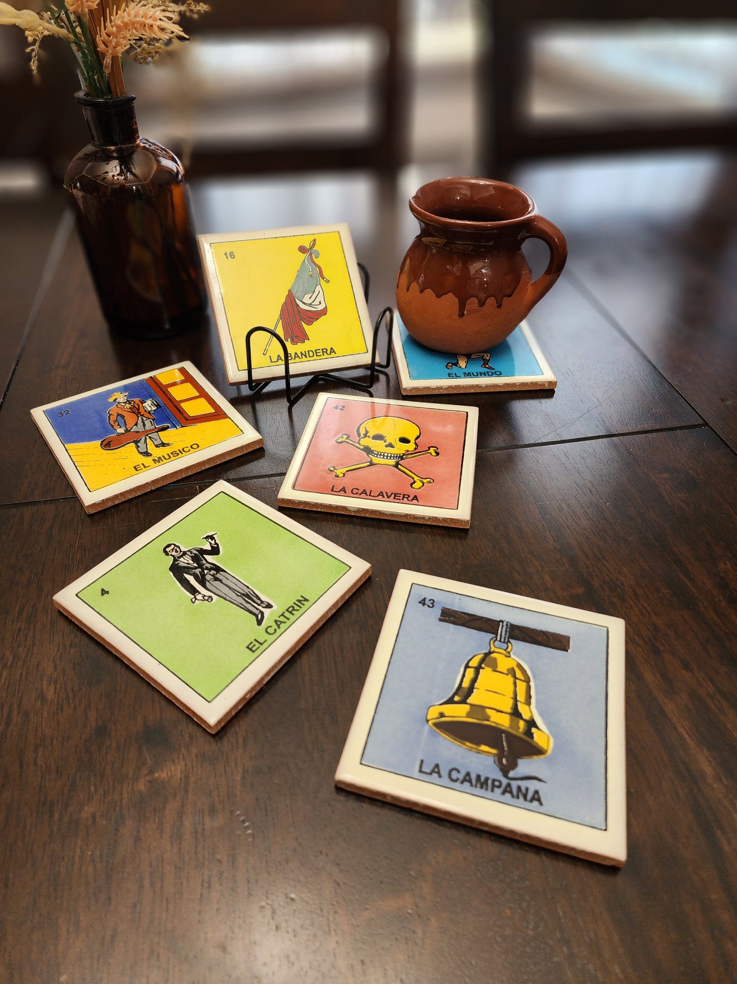 Set of colorful playing loteria inspired ceramic coasters on a wooden surface