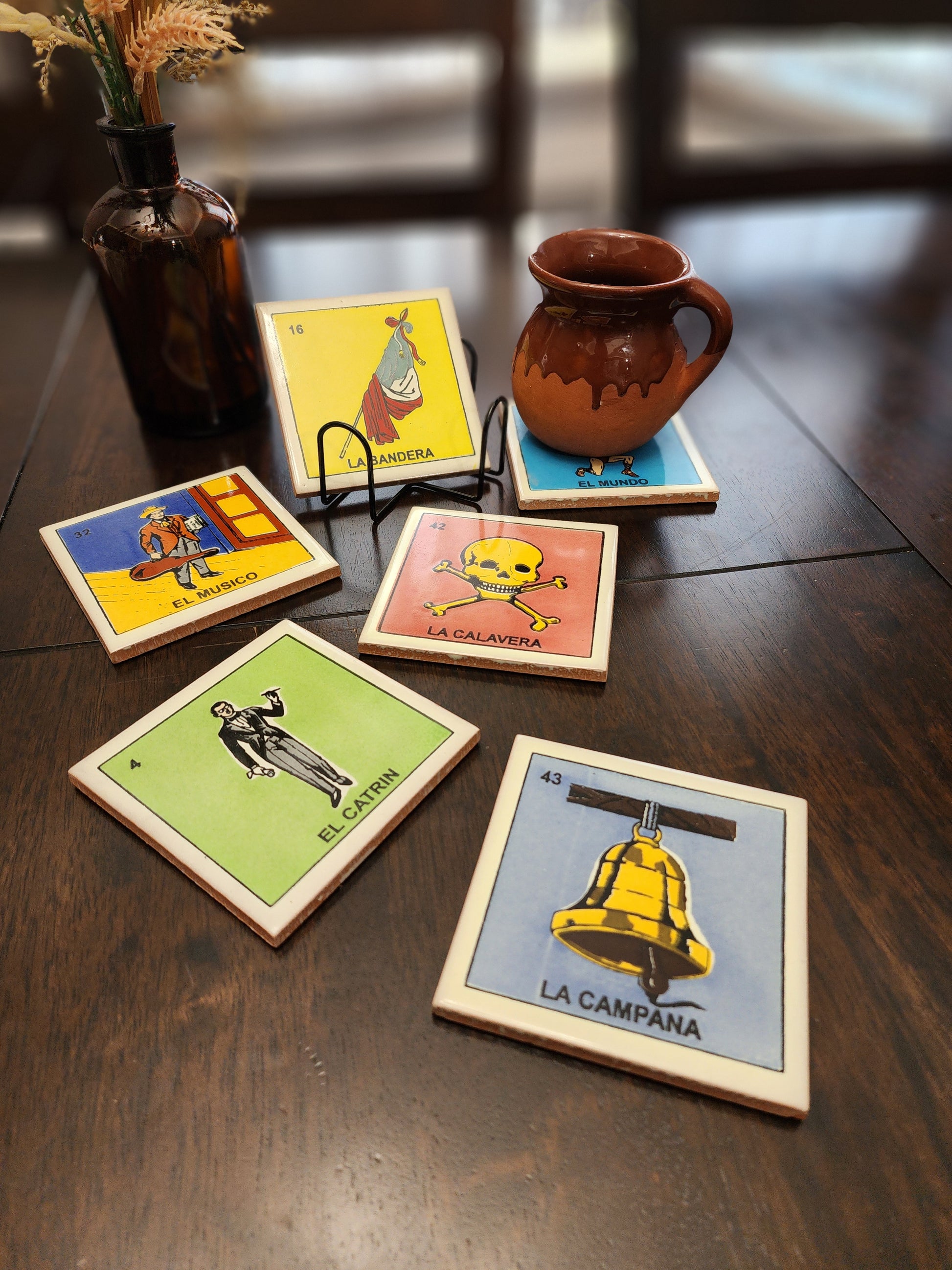 Set of colorful playing loteria inspired ceramic coasters on a wooden surface