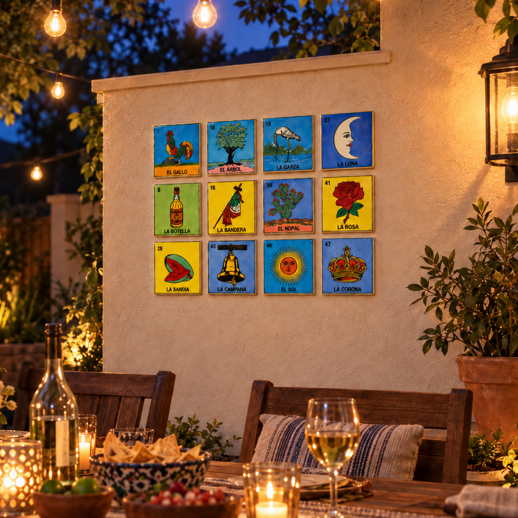 Roots & Memories 12-piece Lotería tile set displayed on an outdoor patio wall above a dining table with string lights.
