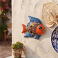 Blue and orange Talavera-style ceramic fish wall décor displayed on a stucco wall in a coastal-inspired outdoor space.