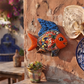 Blue and orange Talavera-style ceramic fish wall décor displayed on a stucco wall in a Mexican-inspired outdoor space.