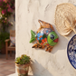 Green and orange Talavera-style ceramic fish wall décor displayed on a stucco wall in a coastal-inspired outdoor space.