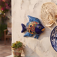 Navy blue and light blue Talavera-style ceramic fish wall décor displayed on a stucco wall in a coastal-inspired outdoor space.