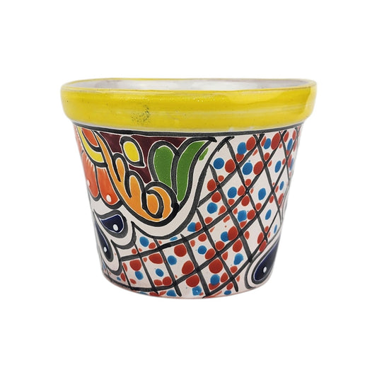 Yellow rim ceramic planter with red and blue dots in a black lattice pattern, orange scrollwork, green accents, and deep blue motifs.
