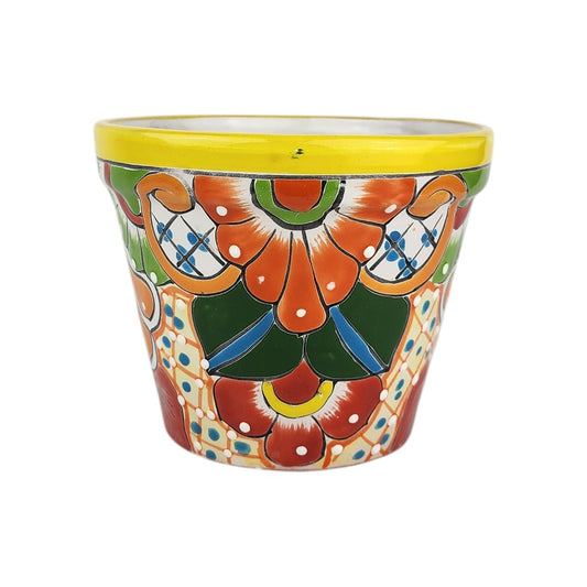 Yellow rim ceramic planter with orange and red flowers, deep green leaves, blue accents, golden-orange scrollwork, and white dotted details.
