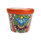 Red orange rim ceramic planter with sky blue petals, green leaves, burgundy and yellow accents, and long orange teardrop shapes.
