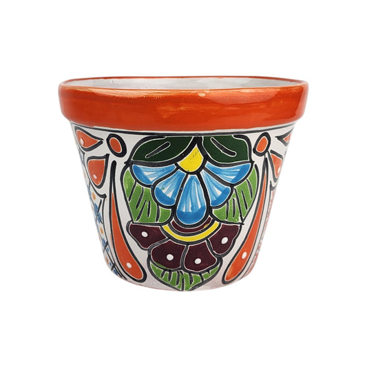 Red orange rim ceramic planter with blue and burgundy floral motifs, green leaves, long orange teardrops, yellow accents, and white dots.

