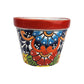 Red rim ceramic planter with sky blue and red flowers, orange scrollwork, green leaves, deep blue teardrops, yellow accents, and white dots.
