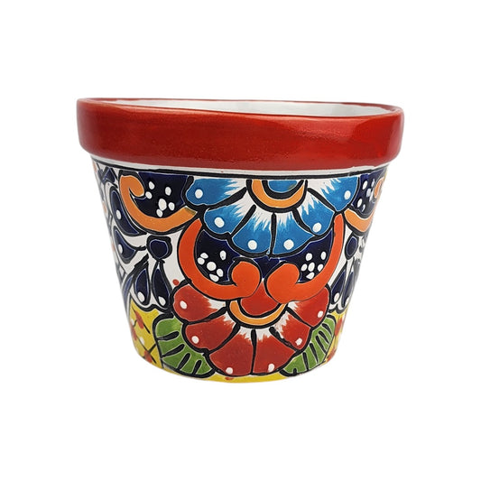 Red rim ceramic planter with sky blue and red flowers, orange scrollwork, green leaves, deep blue teardrops, yellow accents, and white dots.
