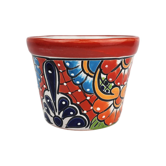 Red rim ceramic planter with deep blue petals, sky blue and red-orange flowers, golden scrollwork, and a red lattice background with white dots.

