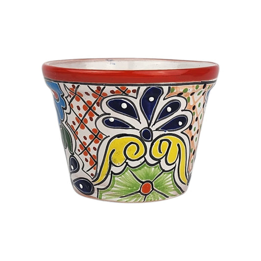 Red rim ceramic planter with deep blue petals, yellow scrollwork, a green flower, and dotted lattice patterns on a white background.