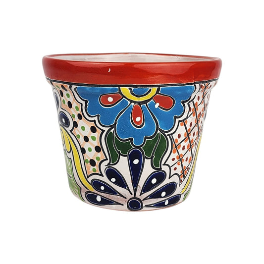 Red rim ceramic planter with a sky blue flower, deep blue petals, green leaves, yellow scrollwork, and dotted lattice patterns.
