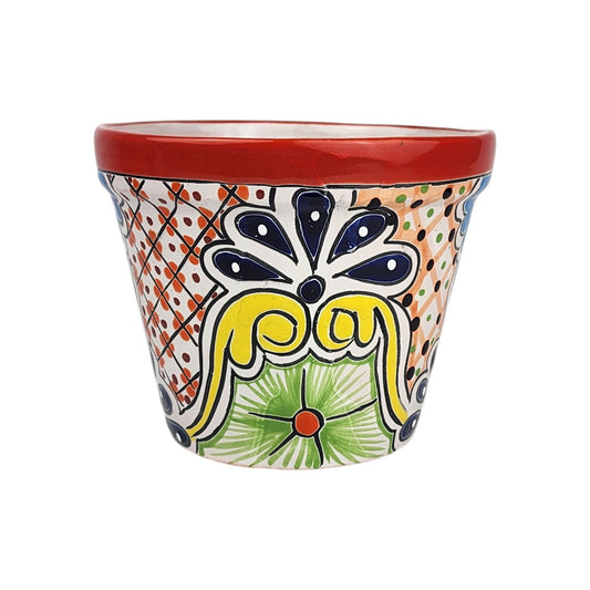 Red rim ceramic planter with deep blue teardrop petals, yellow scrollwork, a green flower with an orange center, and dotted lattice panels.
