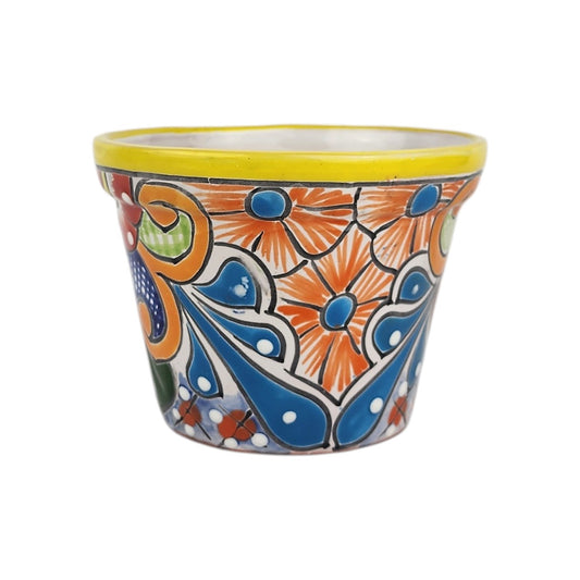 Yellow rim ceramic planter with orange flowers, blue centers, sweeping blue teardrop motifs, and green accents on a white background.